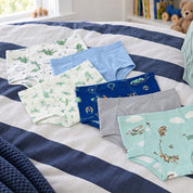 Bellabu Bear boys' bamboo briefs 7-pack laid out on a navy striped duvet: dinosaurs, sky blue, dragonflies, racing cars, grey, aeroplanes and sage